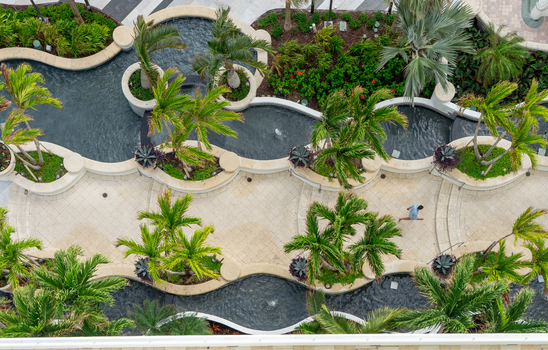 Aerial view of a landscaped courtyard with curved water features lush palm trees and stone walkways in Miami Florida United States. Aerial view of a landscaped courtyard with curved water features lush palm trees and stone walkways in Miami Florida United States.