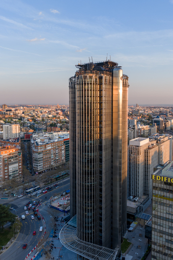 Aerial view of the Torre Europa skyscraper featuring a modern glass and steel facade illuminated by warm sunset light surrounded by the urban landscape of Madrid Community of Madrid Spain. Aerial view of the Torre Europa skyscraper featuring a modern glass and steel facade illuminated by warm sunset light surrounded by the urban landscape of Madrid Community of Madrid Spain.