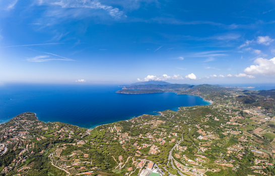Aerial view of the coastal landscape of Lido di Capoliveri with lush green hills Mediterranean vegetation and deep blue sea Lido di Capoliveri Toscana Italy.