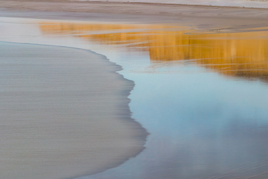 Aerial view of the salt flats at Tuzbair with golden reflections on the water surface and smooth sandy textures in Mangystau District Mangystau Region Kazakhstan.