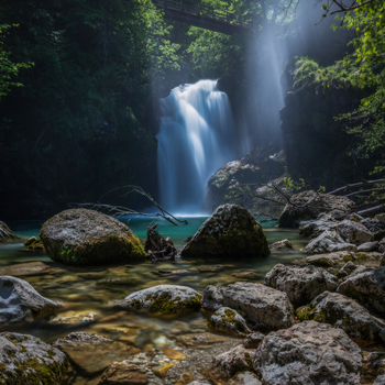 View of the Sum Waterfall in Vintgar Gorge with mossy rocks in the foreground and a wooden bridge above Bled Radovljica Slovenia.