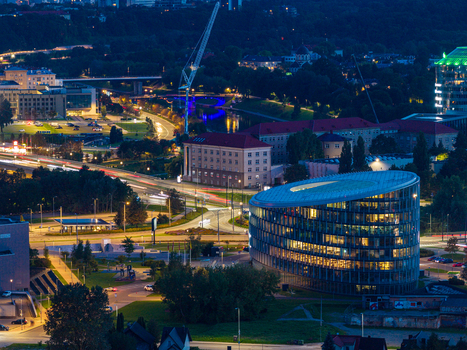 Aerial view of the modern illuminated office building in the city center with surrounding urban roads and light trails at night in Vilnius Vilnius County Lithuania. Aerial view of the modern illuminated office building in the city center with surrounding urban roads and light trails at night in Vilnius Vilnius County Lithuania.