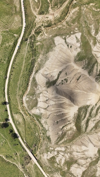 Aerial view of sun scorched earth sculpted by wind and time bisected by a pale ribbon of road winding through the arid landscape Centuripe Sicilia Italy. Aerial view of sun scorched earth sculpted by wind and time bisected by a pale ribbon of road winding through the arid landscape Centuripe Sicilia Italy.