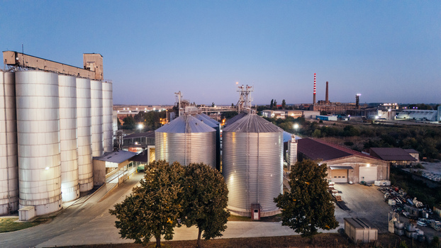 Aerial view of industrial grain silos and storage facilities at dusk with metal structures and surrounding trees in Sremska Mitrovica Vojvodina Serbia. Aerial view of industrial grain silos and storage facilities at dusk with metal structures and surrounding trees in Sremska Mitrovica Vojvodina Serbia.