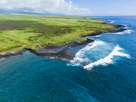 Aerial view of Kalae coastline with green meadows black volcanic rock cliffs and turquoise ocean waves under a cloudy sky Hawaii County Hawaii United States. Aerial view of Kalae coastline with green meadows black volcanic rock cliffs and turquoise ocean waves under a cloudy sky Hawaii County Hawaii United States.
