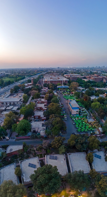 Aerial view of the urban landscape featuring institutional buildings lush green trees and residential rooftops with solar panels in Lahore Punjab Pakistan. Aerial view of the urban landscape featuring institutional buildings lush green trees and residential rooftops with solar panels in Lahore Punjab Pakistan.
