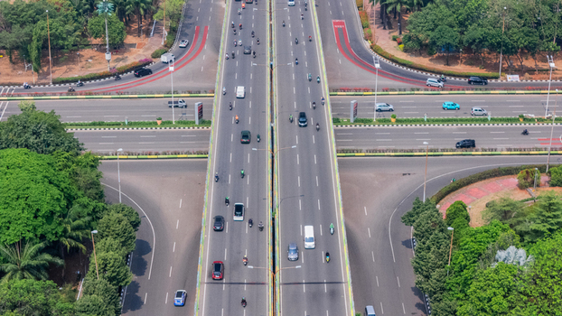 Aerial view of a busy highway interchange with cars and motorcycles driving on multi lane roads surrounded by lush green trees in Jakarta Indonesia. Aerial view of a busy highway interchange with cars and motorcycles driving on multi lane roads surrounded by lush green trees in Jakarta Indonesia.