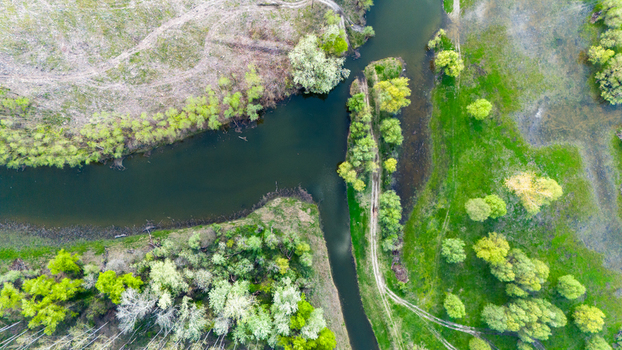 Aerial view of the tranquil river snaking through the vibrant landscape of lush meadows and budding trees reflecting the sky above Kovilj Vojvodina Serbia. Aerial view of the tranquil river snaking through the vibrant landscape of lush meadows and budding trees reflecting the sky above Kovilj Vojvodina Serbia.
