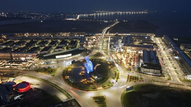 Aerial view of illuminated Orchestra sculpture at roundabout on Golf Island with modern buildings and traffic light trails in Kecamatan Penjaringan Daerah Khusus Ibukota Indonesia. Aerial view of illuminated Orchestra sculpture at roundabout on Golf Island with modern buildings and traffic light trails in Kecamatan Penjaringan Daerah Khusus Ibukota Indonesia.