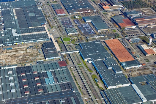 Aerial view of sprawling industrial buildings and parking lots creating a geometric mosaic of textures and tones Sausheim Grand Est France.
