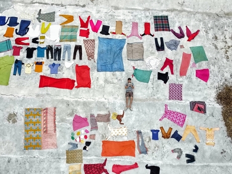 Dinajpur District Bangladesh 26 July 2026 Aerial view of a person lying on a concrete surface surrounded by various colorful clothes laid out to dry in the sun at Jharbari Bazar.