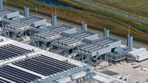Aerial view of the HGB industrial facility featuring complex cooling towers and machinery on rooftops surrounded by paved infrastructure and green fields in Winschoten Groningen Netherlands.