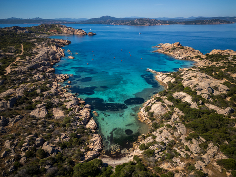 Aerial view of the turquoise waters of Cala Carlotto surrounded by granite rock formations and Mediterranean vegetation in La Maddalena Sardinia Italy. Aerial view of the turquoise waters of Cala Carlotto surrounded by granite rock formations and Mediterranean vegetation in La Maddalena Sardinia Italy.
