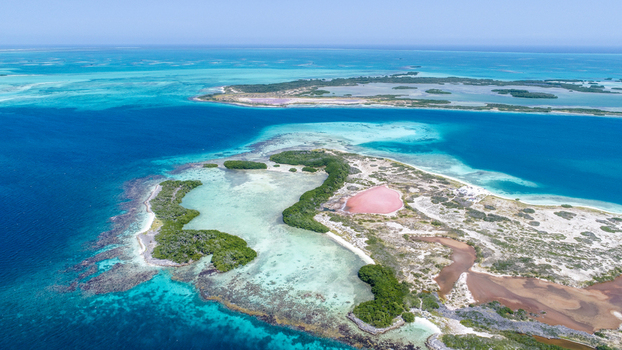 Aerial view of Los Roques archipelago featuring turquoise waters coral reefs lush mangroves and pink salt flats under a clear blue sky in Los Roques Dependencias Federales Venezuela. Aerial view of Los Roques archipelago featuring turquoise waters coral reefs lush mangroves and pink salt flats under a clear blue sky in Los Roques Dependencias Federales Venezuela.
