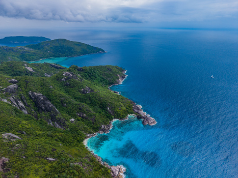 Aerial view of the vivid turquoise waters meeting the rugged green coastline under a cloudy sky Montagne Jasmin Mahe Island Seychelles. Aerial view of the vivid turquoise waters meeting the rugged green coastline under a cloudy sky Montagne Jasmin Mahe Island Seychelles.