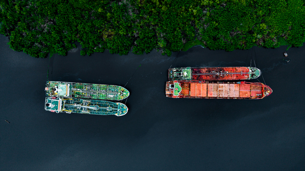 Aerial view of cargo ships anchored in the waterway near lush green mangroves in Lagos Lagos Nigeria.