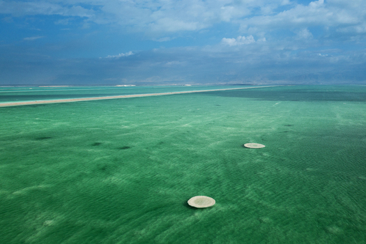 Aerial view of the shimmering turquoise waters of the Dead Sea revealing intricate salt patterns and circular formations under a dramatic sky Ein Bokek Southern District Israel. Aerial view of the shimmering turquoise waters of the Dead Sea revealing intricate salt patterns and circular formations under a dramatic sky Ein Bokek Southern District Israel.