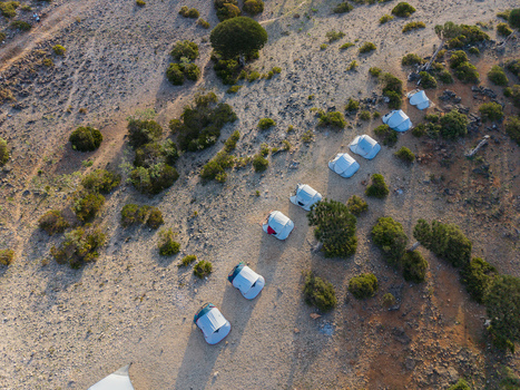 Aerial view of a neat row of white tents contrasting against the arid rocky landscape dotted with sparse greenery Firmihin Socotra Yemen.