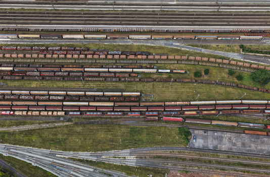 Aerial view of a busy railway yard featuring numerous parallel tracks filled with various freight train cars surrounded by grassy areas and industrial infrastructure in Saalfeld Thuringia Germany. Aerial view of a busy railway yard featuring numerous parallel tracks filled with various freight train cars surrounded by grassy areas and industrial infrastructure in Saalfeld Thuringia Germany.