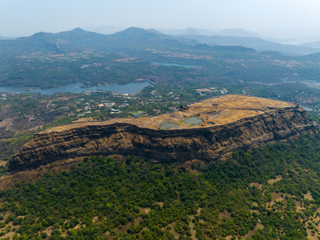 Aerial view of Korigad Fort featuring its rugged plateau ancient stone walls and small water reservoirs surrounded by lush green forests and distant hills in Peth Shahapur Maharashtra India. Aerial view of Korigad Fort featuring its rugged plateau ancient stone walls and small water reservoirs surrounded by lush green forests and distant hills in Peth Shahapur Maharashtra India.