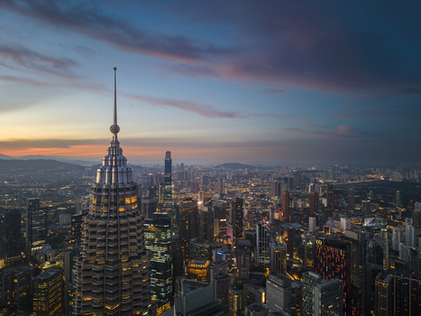 Kuala Lumpur Malaysia 11 March 2026 Aerial view of the Petronas Twin Towers spire overlooking the illuminated city skyline under a sunset sky.