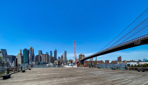 View of the Brooklyn Bridge and the Manhattan skyline from a wooden pier under a clear blue sky in New York New York United States. View of the Brooklyn Bridge and the Manhattan skyline from a wooden pier under a clear blue sky in New York New York United States.