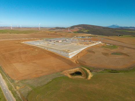 Aerial view of an electrical substation and wind turbines across rolling agricultural fields under a clear blue sky in Swellendam Western Cape South Africa. Aerial view of an electrical substation and wind turbines across rolling agricultural fields under a clear blue sky in Swellendam Western Cape South Africa.