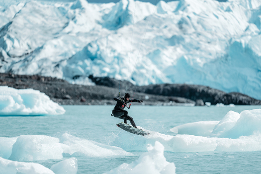 View of a kitesurfer performing a jump on the turquoise waters of Lake Argentino in front of the massive ice wall of the Perito Moreno glacier Perito Moreno Santa Cruz Province Argentina. View of a kitesurfer performing a jump on the turquoise waters of Lake Argentino in front of the massive ice wall of the Perito Moreno glacier Perito Moreno Santa Cruz Province Argentina.