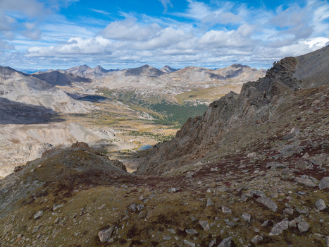 Aerial view of Mount Harvard and the surrounding rocky alpine landscape with sparse vegetation and scattered boulders under a blue sky with clouds in Buena Vista Colorado United States. Aerial view of Mount Harvard and the surrounding rocky alpine landscape with sparse vegetation and scattered boulders under a blue sky with clouds in Buena Vista Colorado United States.