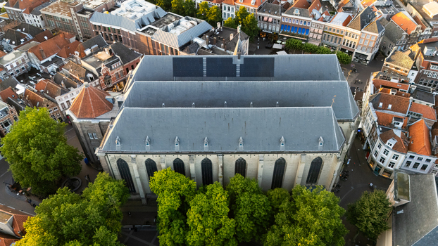 Aerial view of the Grote Kerk surrounded by historic city rooftops lush green trees and narrow streets in Zwolle Overijssel Netherlands.