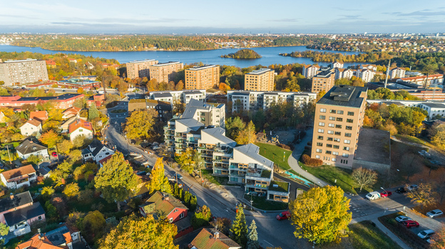 Aerial view of modern apartment buildings surrounded by colorful autumn trees and lush greenery in a residential neighborhood near a lake in Sweden. Aerial view of modern apartment buildings surrounded by colorful autumn trees and lush greenery in a residential neighborhood near a lake in Sweden.