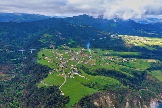 Aerial view of the rural landscape near the Silence Beach Viewpoint featuring the village of Castaneras green meadows and a highway viaduct in Cudillero Asturias Spain.