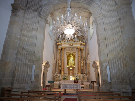 View of the ornate altar and crystal chandelier inside the Santuario de la Virgen Peregrina with wooden pews and stone columns in Pontevedra Pontevedra Spain.