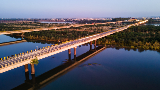 Aerial view of the long Jhelum Bridge spanning across the Jhelum River with lush green banks and the city skyline under a soft twilight sky Jhelum Punjab Pakistan. Aerial view of the long Jhelum Bridge spanning across the Jhelum River with lush green banks and the city skyline under a soft twilight sky Jhelum Punjab Pakistan.
