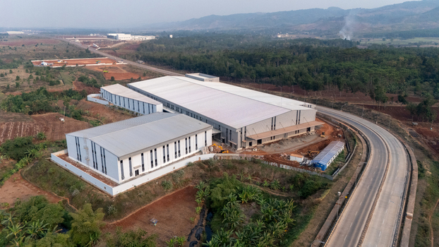 Aerial view of Kawasan Industri Terpadu Batang featuring large industrial warehouse buildings and construction sites near a highway in Kecamatan Gringsing Jawa Tengah Indonesia.