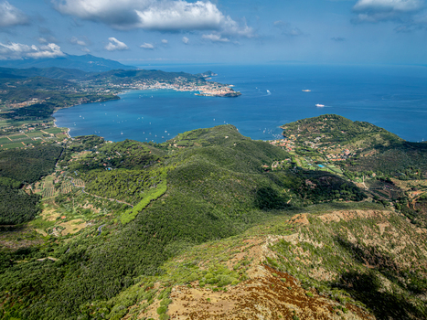 Aerial view of Castello del Volterraio overlooking the lush green hills and the blue bay of the island Portoferraio Toscana Italy.