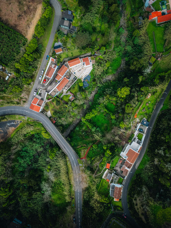 Aerial view of roads curving around buildings with red roofs nestled amid lush greenery a vibrant tapestry of nature and architecture Agua de Alto Azores Portugal.