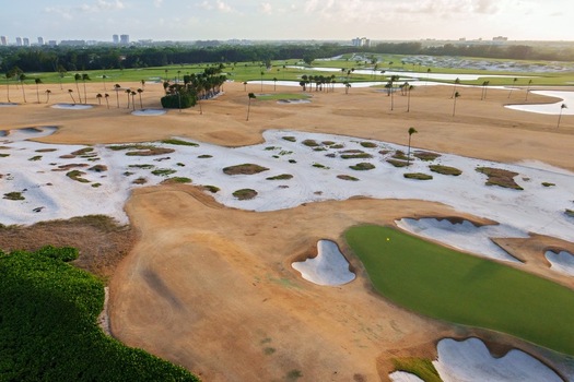 Aerial view of a golf course s sand traps and green grass surrounded by brown grass and palm trees Juno Florida United States.
