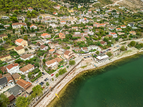 Aerial view of Shiroka village with terracotta rooftops narrow streets and lush hills along the lake shore Shiroka Shkoder County Albania.