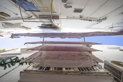 View of laundry hanging on lines between traditional white buildings in a narrow alleyway Polignano a Mare Apulia Italy.
