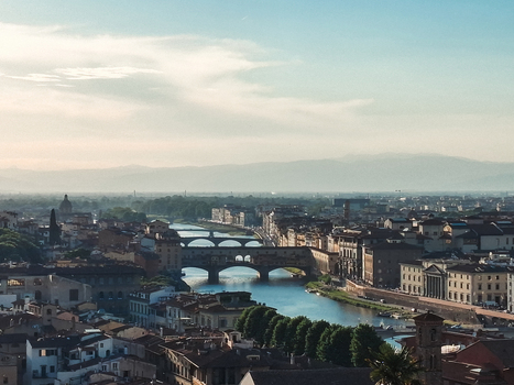View of the historic Ponte Vecchio spanning the Arno River surrounded by traditional buildings and hills in Florence Tuscany Italy. View of the historic Ponte Vecchio spanning the Arno River surrounded by traditional buildings and hills in Florence Tuscany Italy.