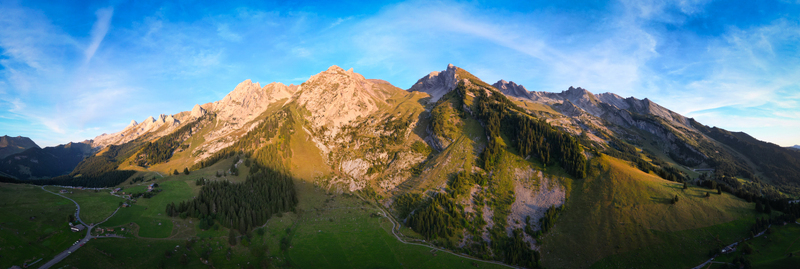 Aerial view of rugged peaks bathed in golden sunlight cascade down to lush green valleys a tapestry of nature s artistry La Clusaz Auvergne Rhône Alpes France. Aerial view of rugged peaks bathed in golden sunlight cascade down to lush green valleys a tapestry of nature s artistry La Clusaz Auvergne Rhône Alpes France.