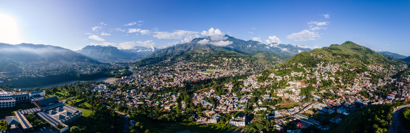 Aerial view of the sprawling city nestled in a lush valley between majestic green mountains under a clear blue sky with a winding river Muzaffarabad Azad Kashmir Pakistan. Aerial view of the sprawling city nestled in a lush valley between majestic green mountains under a clear blue sky with a winding river Muzaffarabad Azad Kashmir Pakistan.
