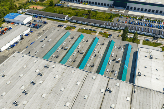 Aerial view of a large industrial warehouse facility with green skylights parking lots and surrounding logistics buildings in Prague Prague Czechia.
