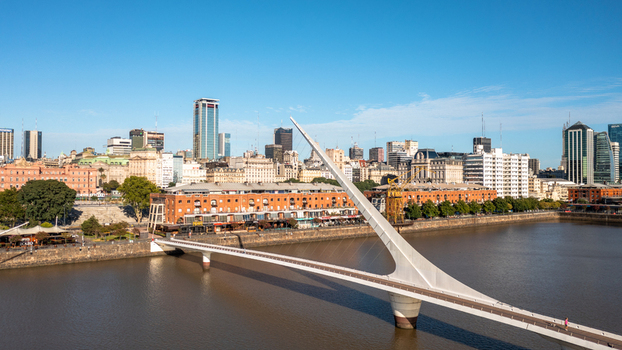 Buenos Aires Argentina 11 July 2022 Aerial view of Puente de la Mujer bridge in Puerto Madero with the city skyline and modern buildings in the background under a clear blue sky.