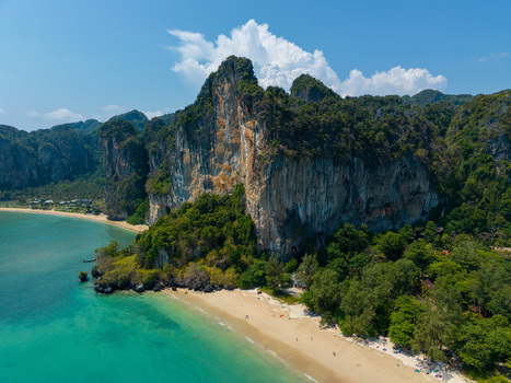 Aerial view of Railay Beach featuring dramatic limestone cliffs lush tropical vegetation and turquoise waters along the sandy coastline in Ao Nang Krabi Thailand.