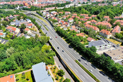 Aerial view of the A73 highway passing through residential neighborhoods with red roofed houses and lush green trees in Nurnberg Bayern Germany. Aerial view of the A73 highway passing through residential neighborhoods with red roofed houses and lush green trees in Nurnberg Bayern Germany.