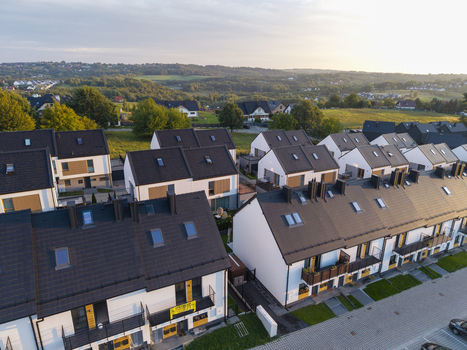 Aerial view of modern residential townhouses with dark roofs and white facades in a suburban neighborhood in Poland. Aerial view of modern residential townhouses with dark roofs and white facades in a suburban neighborhood in Poland.