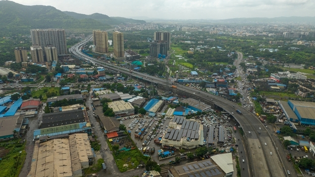 Aerial view of the JNPT Interchange with surrounding industrial buildings high rise residential towers and lush green hills in the background in Navi Mumbai Maharashtra India. Aerial view of the JNPT Interchange with surrounding industrial buildings high rise residential towers and lush green hills in the background in Navi Mumbai Maharashtra India.