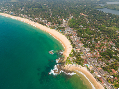 Aerial view of the turquoise coastline with sandy beaches rocky shores and lush tropical vegetation along the coastal road in Dodanduwa Southern Province Sri Lanka. Aerial view of the turquoise coastline with sandy beaches rocky shores and lush tropical vegetation along the coastal road in Dodanduwa Southern Province Sri Lanka.